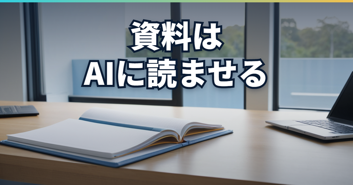 会議室の窓辺の机に、青い表紙のノートが開いて置かれ、右にノートPC